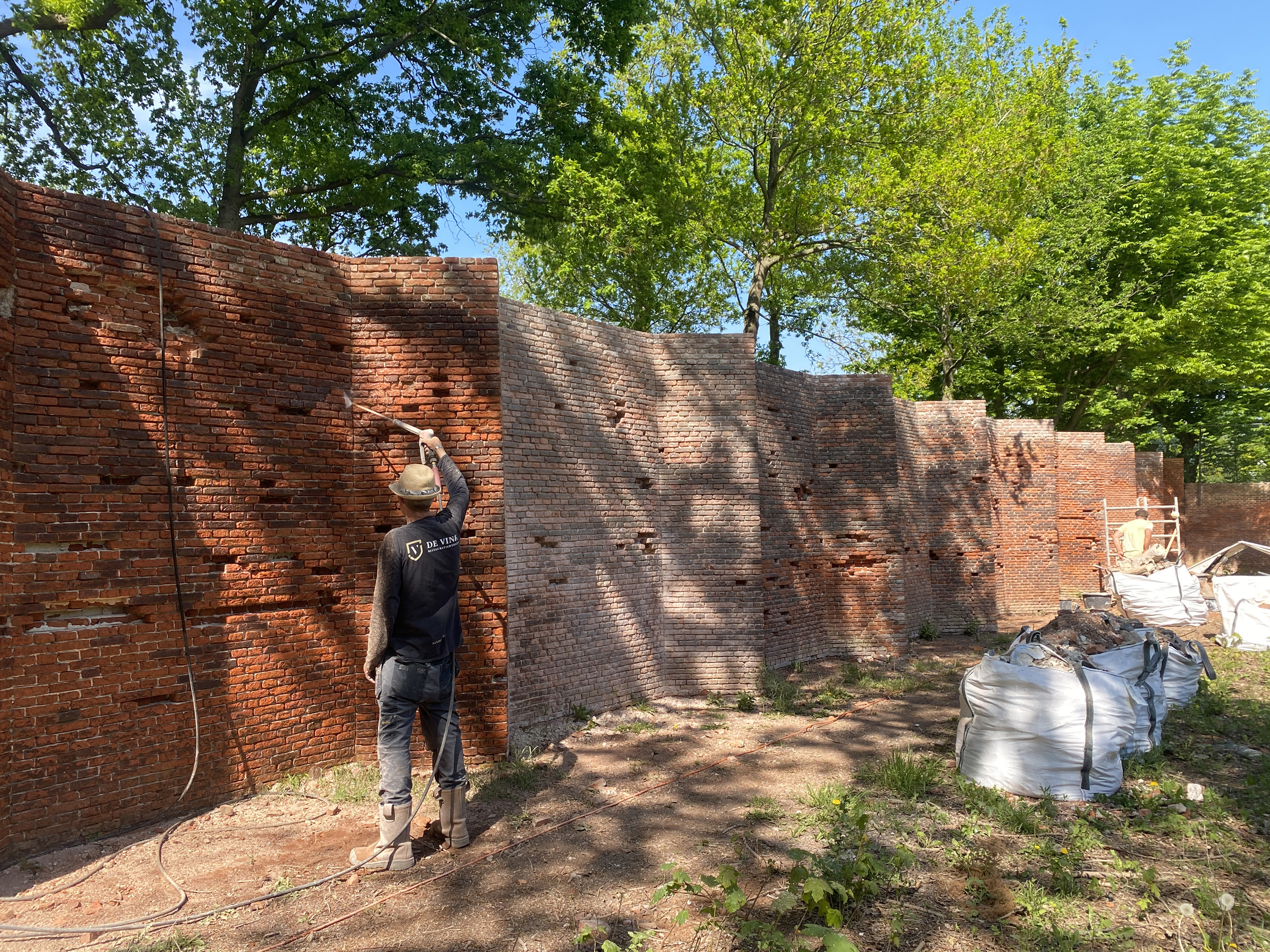 Reinigen van de retranchementsmuur (tuinmuur) op Landgoed Marlot tijdens restauratie