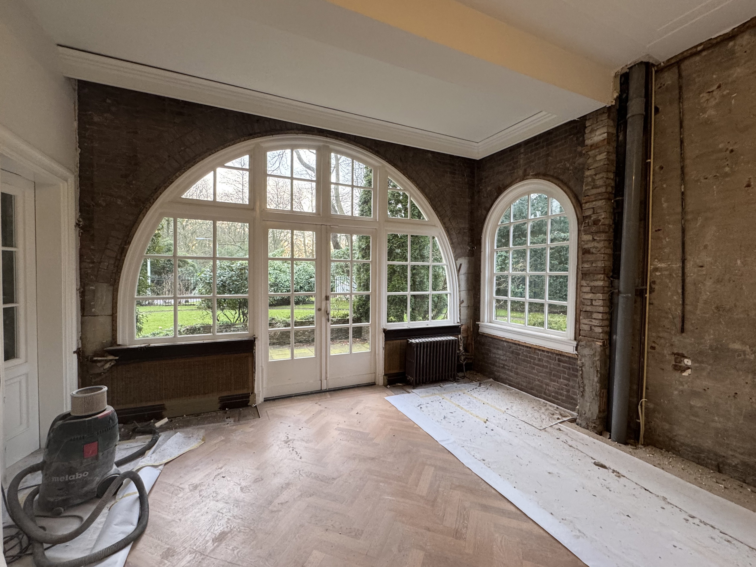 Woonkamer met getoogd raam gestript voor het aanbrengen van isolatie tegen de metselwerkwand